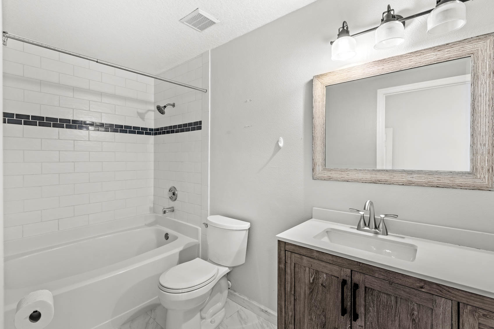 bathroom with white tub and toilet with brown sink cabinet